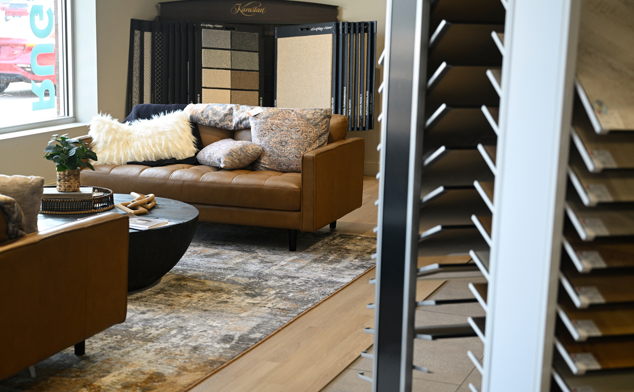 showroom living room display with laminate floors, carpet and leather couches